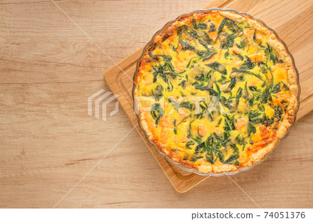 Seafood salmon fish and spinach leaves quiche pie - homemade recipe pie on wooden table background with copy space, selective focus. Top view 74051376