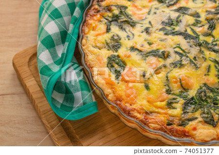 Close up view of salmon fish or seafood and spinach quiche pie - homemade recipe pie on wooden table background with copy space, selective focus. Top view 74051377