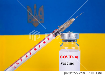 COVID-19 vaccine vial against Ukrainian flag on blue background with copy space for text - coronavirus vaccine doses, vaccination in Ukraine concept. Selective focus COVID-19 vaccine vial against Ukrainian flag on blue background with copy space for text - coronavirus vaccine doses, vaccination in Ukraine concept. Selective focus 74051381
