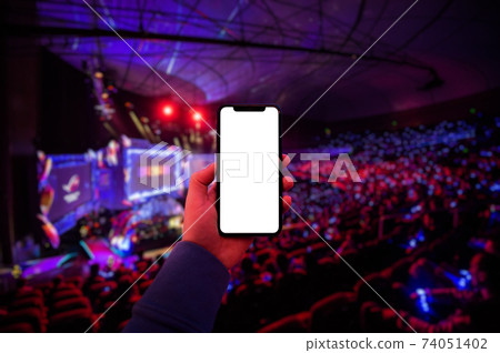 Man's hand using digital application on the mobile smart phone at esport event at big arena. Blank screen with copy space. Man's hand using digital application on the mobile smart phone at esport event at big arena. Blank screen with copy space. 74051402