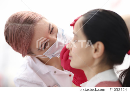Beautician in protective mask making eyebrow modeling for client 74052524