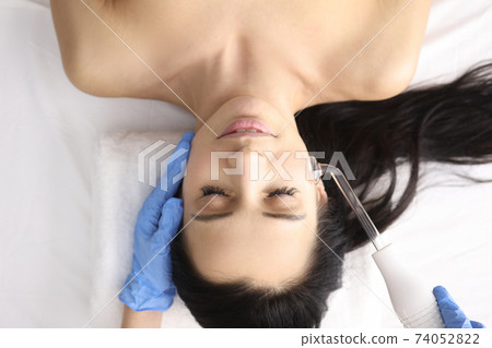 Doctor in gloves doing facial massage with darsonval Doctor in gloves doing facial massage with darsonval 74052822