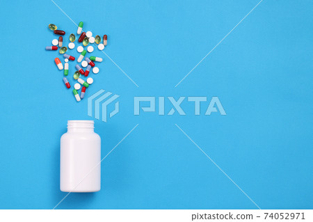 Many multicolored capsules are expelled from jar closeup 74052971
