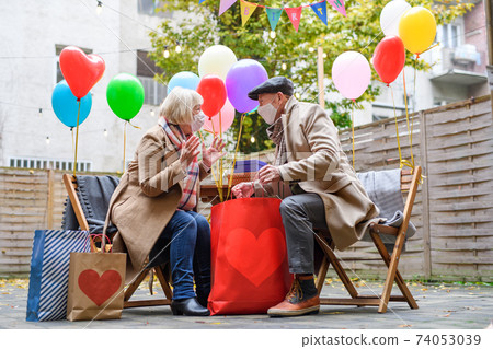 Happy senior partners in outdoor cafe in city, couple celebrating birthday. Coronavirus concept. 74053039
