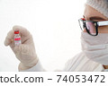 Close up of young female doctor holding and looking at a glass bottle of coronavirus vaccine. Concept of coronavirus vaccination 74053472