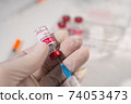 Closeup female doctor holds a syringe and a bottle of coronavirus vaccine. Concept of treatment of coronavirus infection, COVID-19 vaccination 74053473