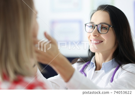 Female doctor palpating patients submandibular lymph nodes 74053622