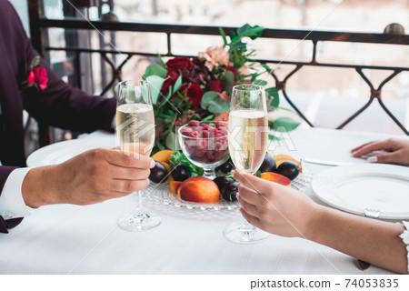 Glasses with champagne drink in bride and groom hands. Happy newlyweds drinking. Loving couple created new family. Glasses with champagne drink in bride and groom hands. Happy newlyweds drinking. Loving couple created new family. 74053835