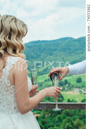 Glasses with red champagne drink. groom pouring wine. Happy newlyweds drinking. Loving couple created new family. 74053862