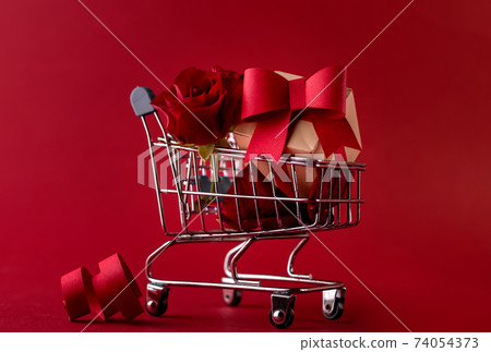 St. Valentine's Festive sale concept banner with gift box rose, and red paper hearts in the shopping cart against a red background. 74054373