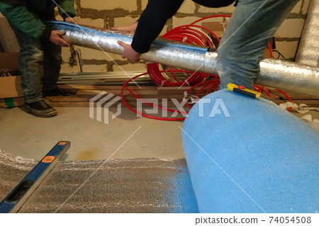 the installer and auxiliary worker wraps the air duct with mineral wool and foil the installer and auxiliary worker wraps the air duct with mineral wool and foil 74054508