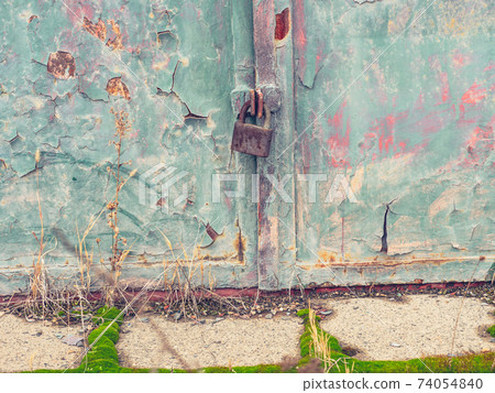 Obsolete green gate or door with padlock. Cracked painted surface Obsolete green gate or door with padlock. Cracked painted surface 74054840