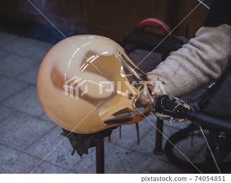 Man artists hands working on a Blown Glass Piece. Shaping glass bowl Man artists hands working on a Blown Glass Piece. Shaping glass bowl 74054851