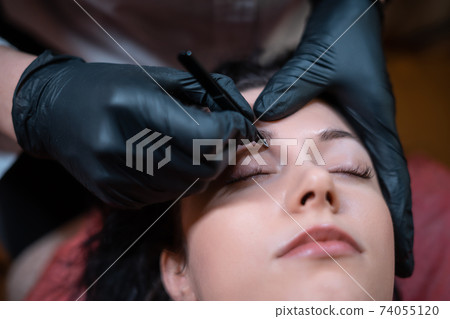 beautiful female at beautician on eyebrows correction procedure with tweezers beautiful female at beautician on eyebrows correction procedure with tweezers 74055120