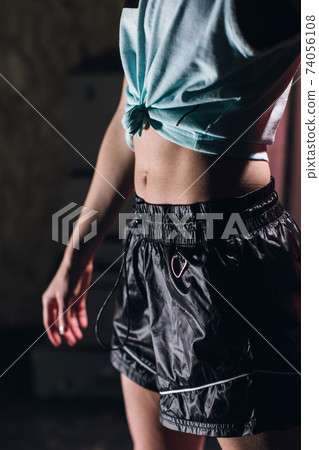 Young girl stands in an atmospheric gym. Close-up of a girl's stomach 74056108