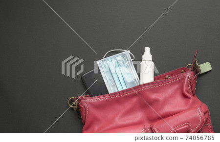 Woman red handbag with face mask, hand sanitizer and smartphone. Woman red handbag with face mask, hand sanitizer and smartphone. 74056785
