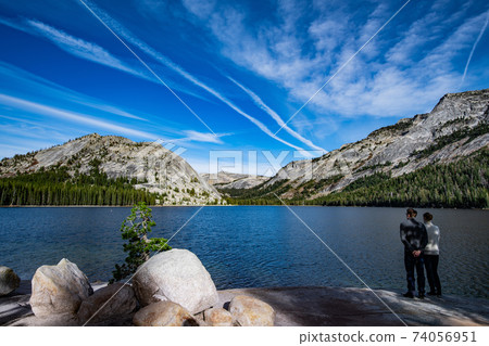 Young couple enjoys views of Tenaya lake in Yosemite, USA: Mountain landscape with mirror lake surrounded by high peaks 74056951