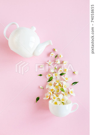 Creative layout of teapot and tea Cup with Jasmine flowers on a pink background. Jasmine tea. Creative layout of teapot and tea Cup with Jasmine flowers on a pink background. Jasmine tea. 74058655