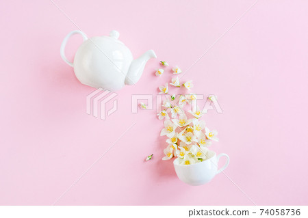 Creative layout of teapot and tea Cup with Jasmine flowers on a pink background. Jasmine tea. Creative layout of teapot and tea Cup with Jasmine flowers on a pink background. Jasmine tea. 74058736