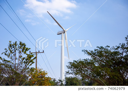 Wind power station. Wind generators stand in agricultural fields on mountain. Wonderful landscape shot from a great height. Modern green energy. 74062979