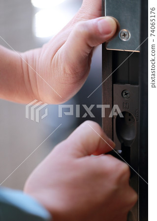 Male repairman maintaining the front door Male repairman maintaining the front door 74065176