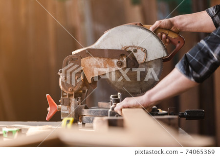 Carpenter man wear protective mask dust working use electronic saw cutting wood. Carpenter man wear protective mask dust working use electronic saw cutting wood. 74065369