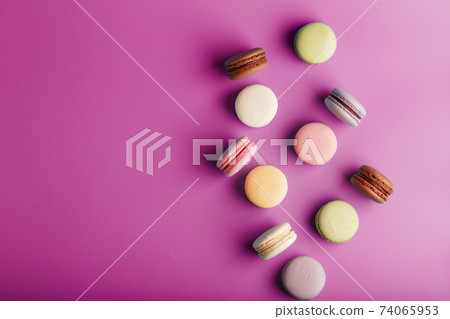 Colorful French macaroni cookies are scattered on a pink background. Colorful French macaroni cookies are scattered on a pink background. 74065953