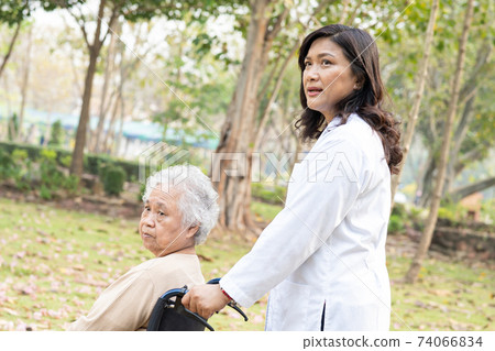 Doctor help and care Asian senior or elderly old lady woman patient sitting on wheelchair at park in nursing hospital ward, healthy strong medical concept. 74066834