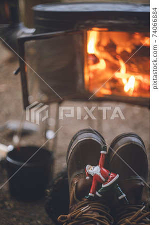 Santa Claus figurine doing yoga and winter camp. Warm fire on a wood stove. 74066884