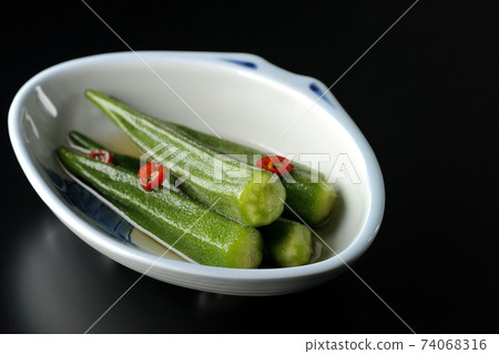 Shooting spicy white pickled okra on a black background Shooting spicy white pickled okra on a black background 74068316