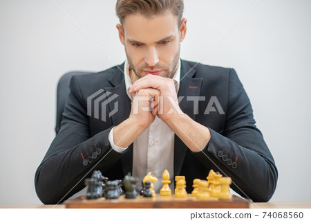 Serious involved man in front of chessboard Serious involved man in front of chessboard 74068560
