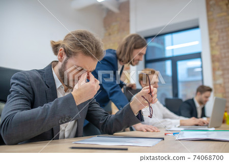 Tired man with closed eyes sitting in office 74068700