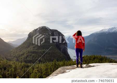 Adventurous Girl Hiking in the mountains during a sunny Autumn Sunset. 74070031