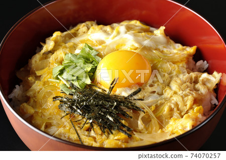 Photographed egg bowl with egg yolk, mitsuba, and chopped seaweed on a black background Photographed egg bowl with egg yolk, mitsuba, and chopped seaweed on a black background 74070257