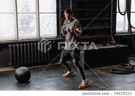 Cool man fighter in boxing bandages trains in the gym. Mixed martial arts 74070323
