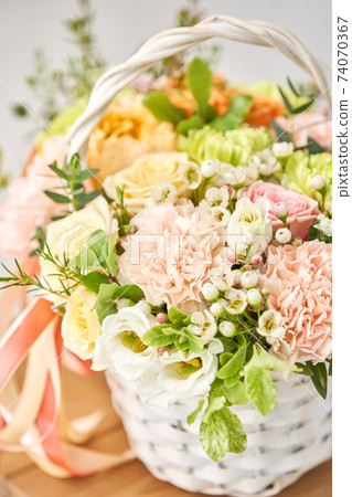 Small flower shop and Flowers delivery. Flower arrangement in Wicker basket. Beautiful bouquet of mixed flowers on wooden table. Handsome fresh bouquet. Small flower shop and Flowers delivery. Flower arrangement in Wicker basket. Beautiful bouquet of mixed flowers on wooden table. Handsome fresh bouquet. 74070367