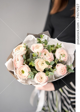 Bunch pale pink ranunculus flowers with green eucalyptus. The work of the florist at a flower shop. 74070427
