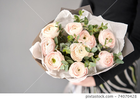 Bunch pale pink ranunculus flowers with green eucalyptus. The work of the florist at a flower shop. 74070428