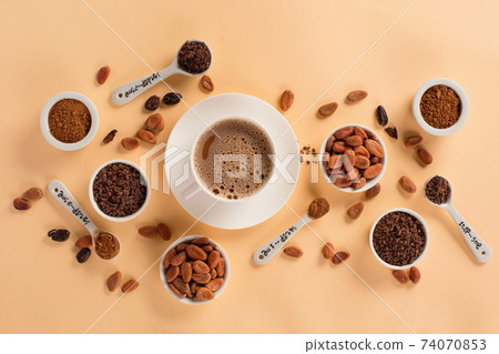 Bowls with aromatic cocoa beans, cocoa nibs, cocoa powder and cup of hot chocolate on natural paper background. 74070853