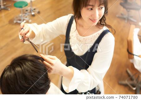 Hair stylist who cuts hair while talking to customers 74071780