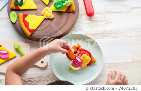 Children's hands playing with felt pizza 74072183