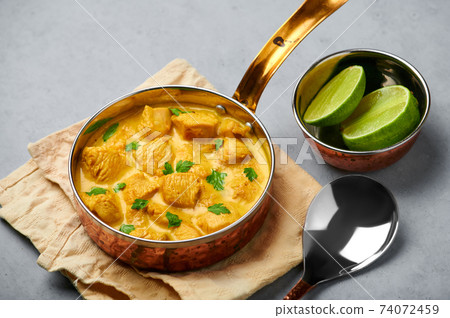 Chicken Korma in copper pan on gray concrete table top. Indian cuisine meat curry dish Chicken Korma in copper pan on gray concrete table top. Indian cuisine meat curry dish 74072459