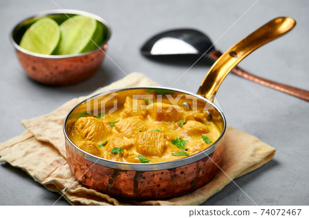 Chicken Korma in copper pan on gray concrete table top. Indian cuisine meat curry dish  74072467