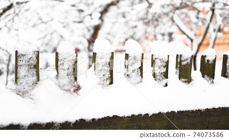 Wooden fence gate covered in white snow at heavy snowing snowstorm 74073586