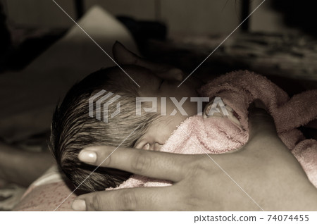 Beautiful Newborn baby boy Close up (6 days old) lying in mother lap in prenatal hospital. Kid wrapped in baby blanket (warm clothing) sleeping looking away. His mother consoling and resting her baby. 74074455