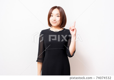 A woman in a mourning dress standing in front of a white background and showing points 74074532