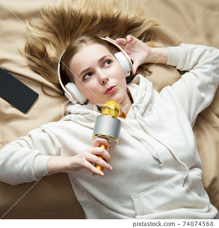 Happy teenage girl singing using microphone and... - Stock Photo [74074568]  - PIXTA