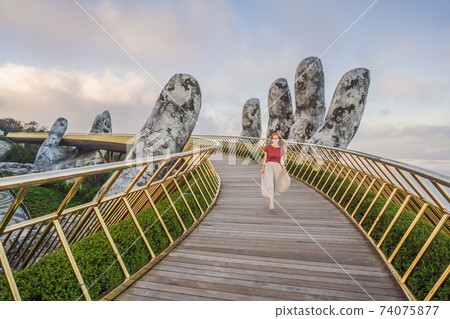 Young woman tourist at Famous tourist attraction - Golden bridge at the top of the Ba Na Hills, Vietnam 74075877