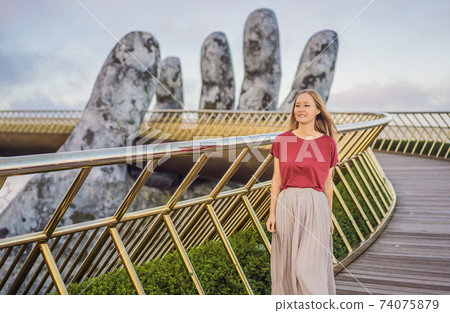 Young woman tourist at Famous tourist attraction - Golden bridge at the top of the Ba Na Hills, Vietnam 74075879