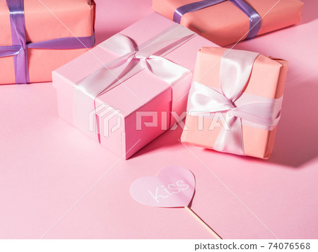 Pink wrapped gift boxes with ribbons on monochrome background Pink wrapped gift boxes with ribbons on monochrome background 74076568